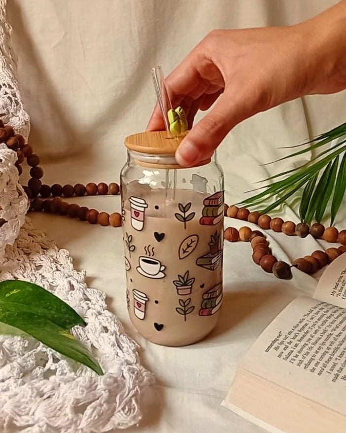 Hand placing a lid on a jar with coffee-themed design, surrounded by decorative elements.