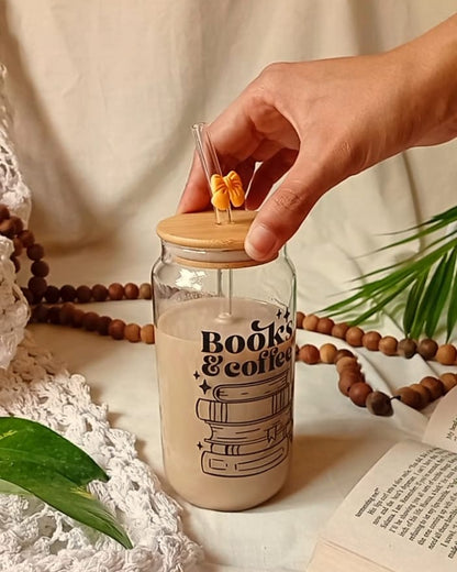 Hand holding a jar labeled 'Book of Coffee' with a plant and book in the background.